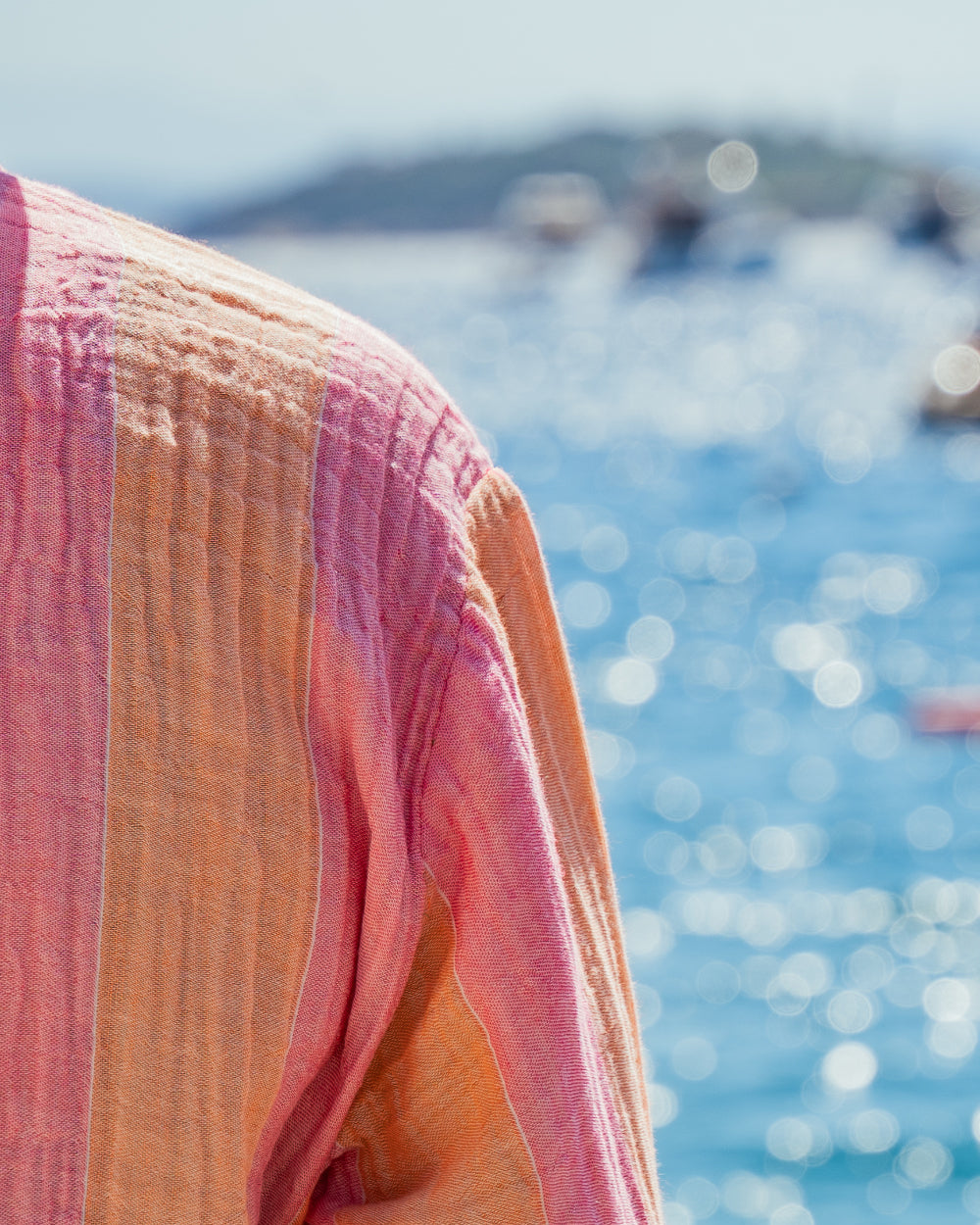 Close-up of a pink and orange robe with a blurred blue water background