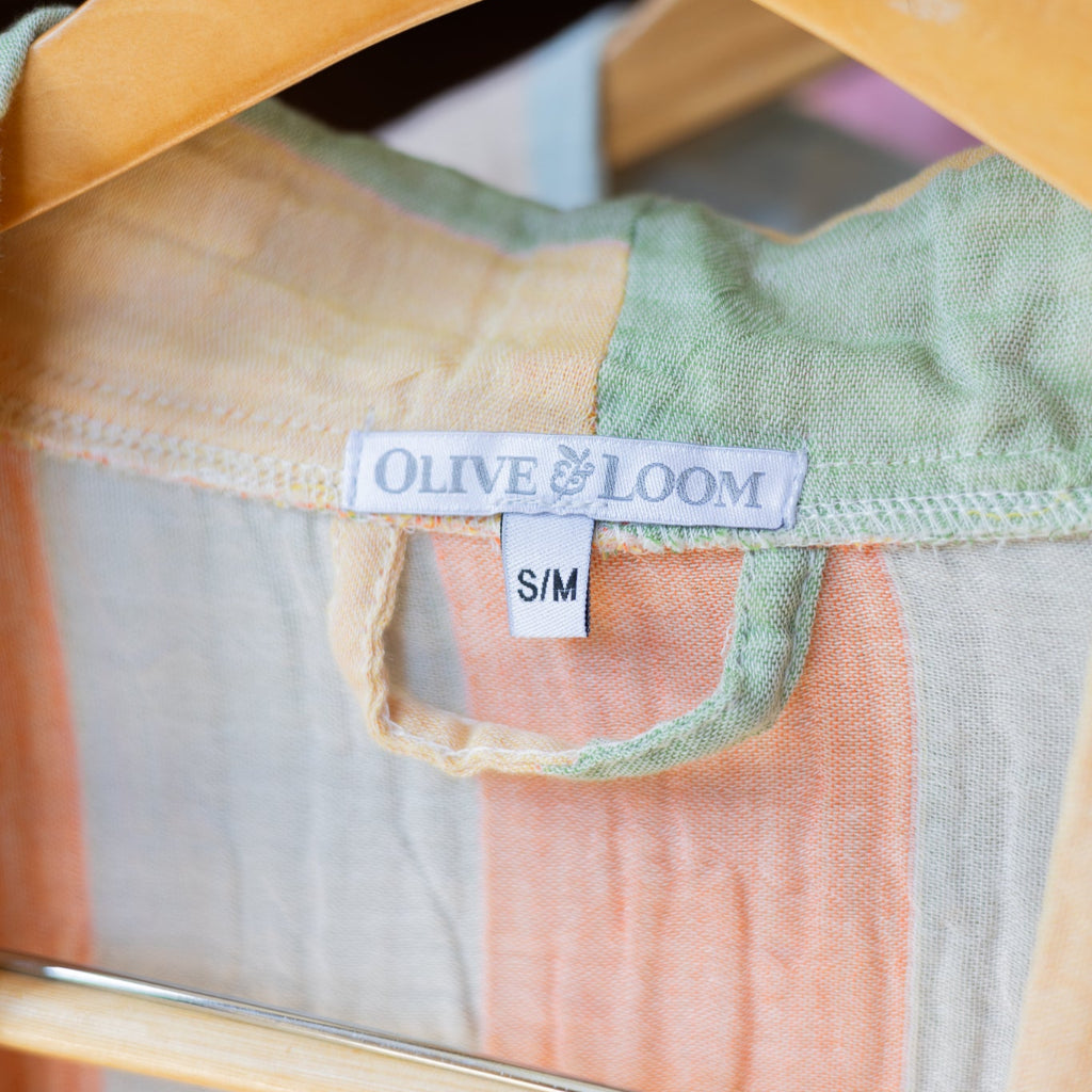 Close-up of a green and pink garment on a hanger with 'Olive & Loom' label.