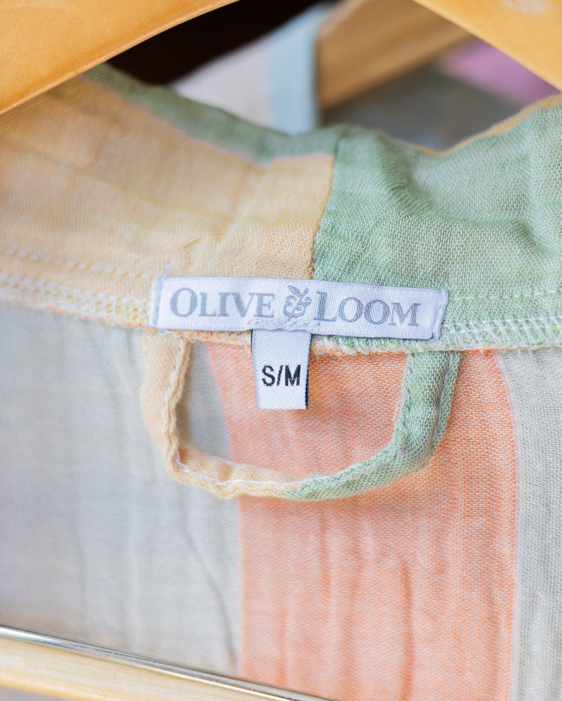Close-up of a green and pink garment on a hanger with 'Olive & Loom' label.