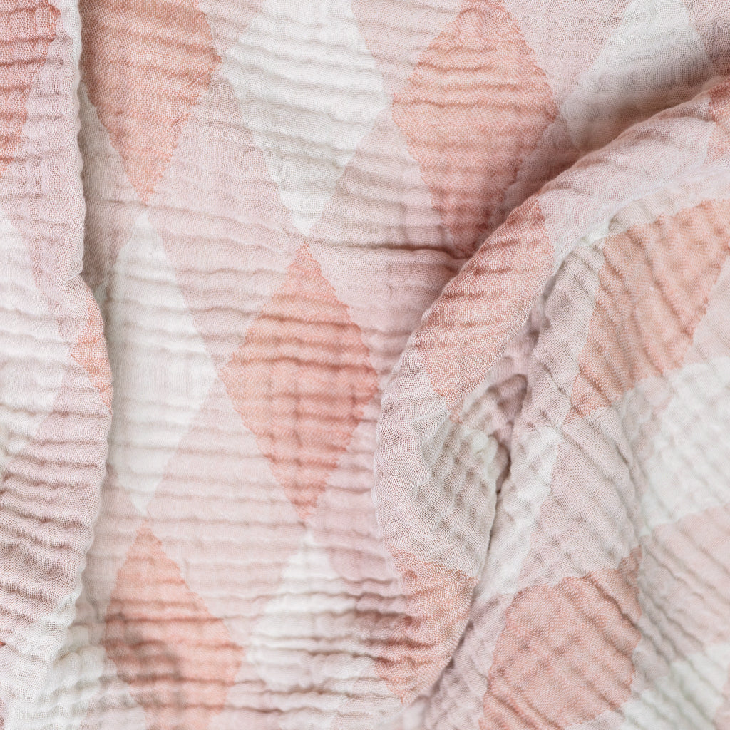 Close-up of baby blanket with pink and beige geometric pattern