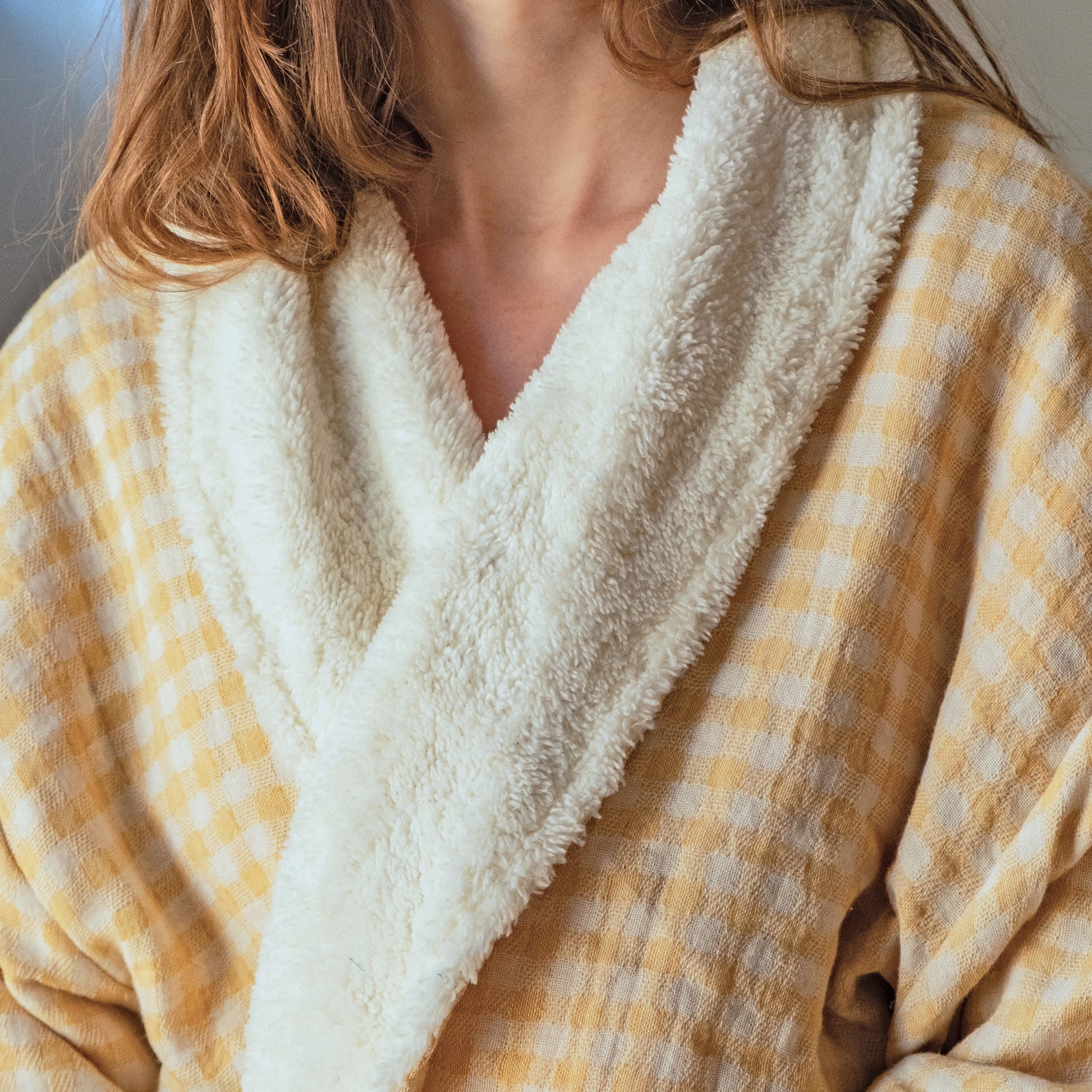 Mustard yellow checkered robe with white fleece lining worn by a young woman