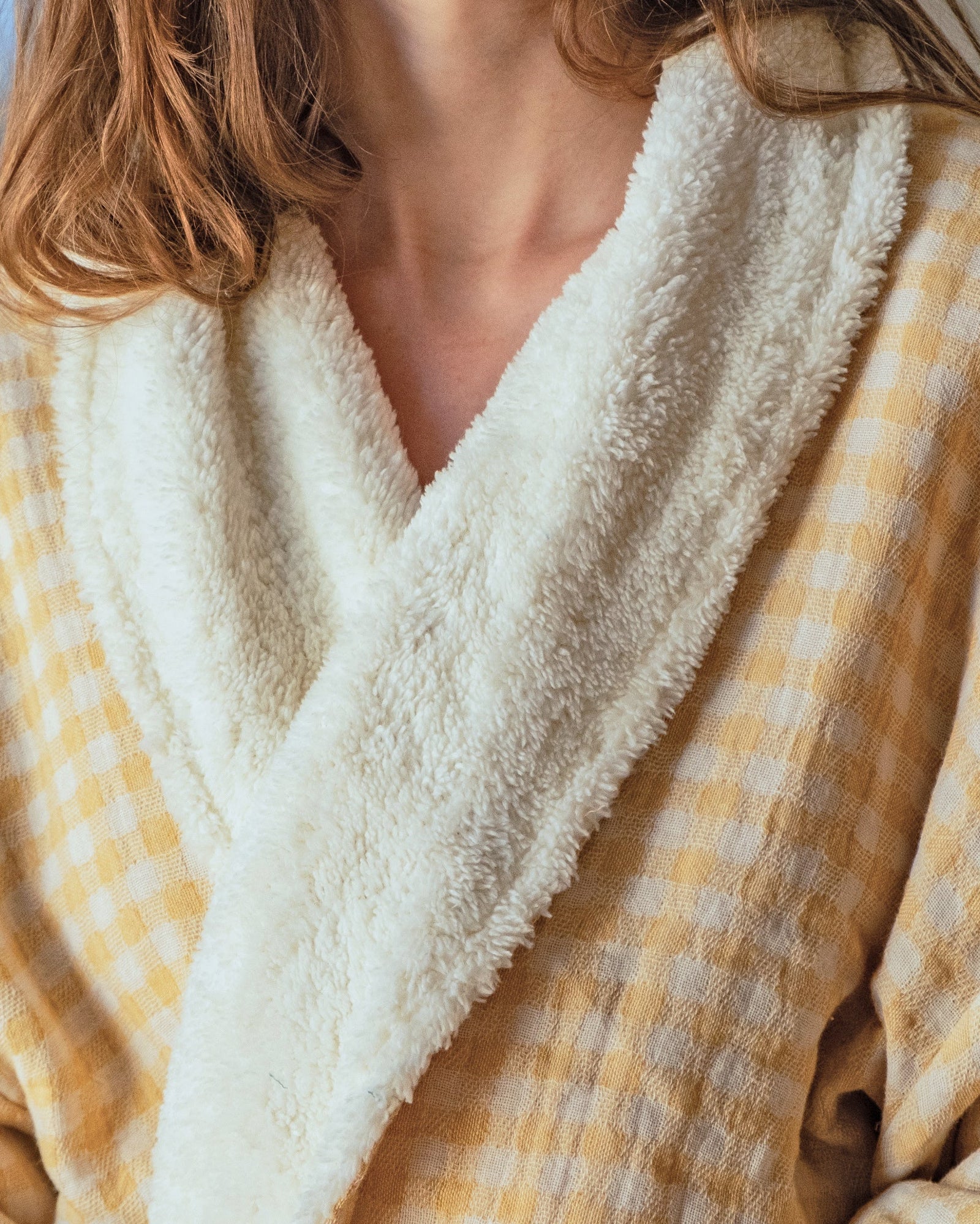 Mustard yellow checkered robe with white fleece lining worn by a young woman