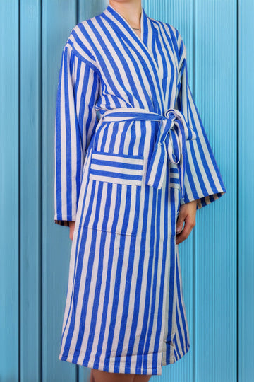 Young woman wearing a blue and white striped robe against a blue background