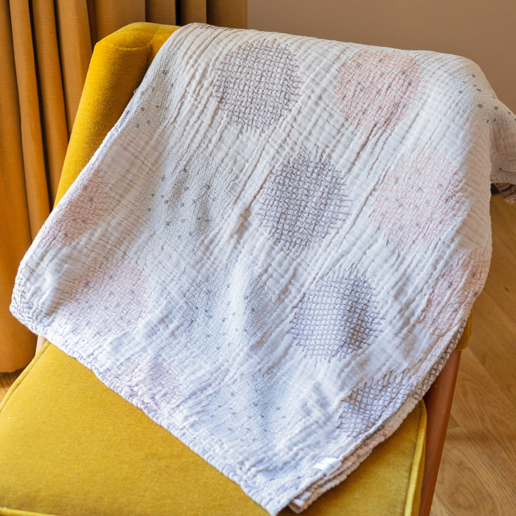 Textured white blanket draped over a yellow chair with a blurred background
