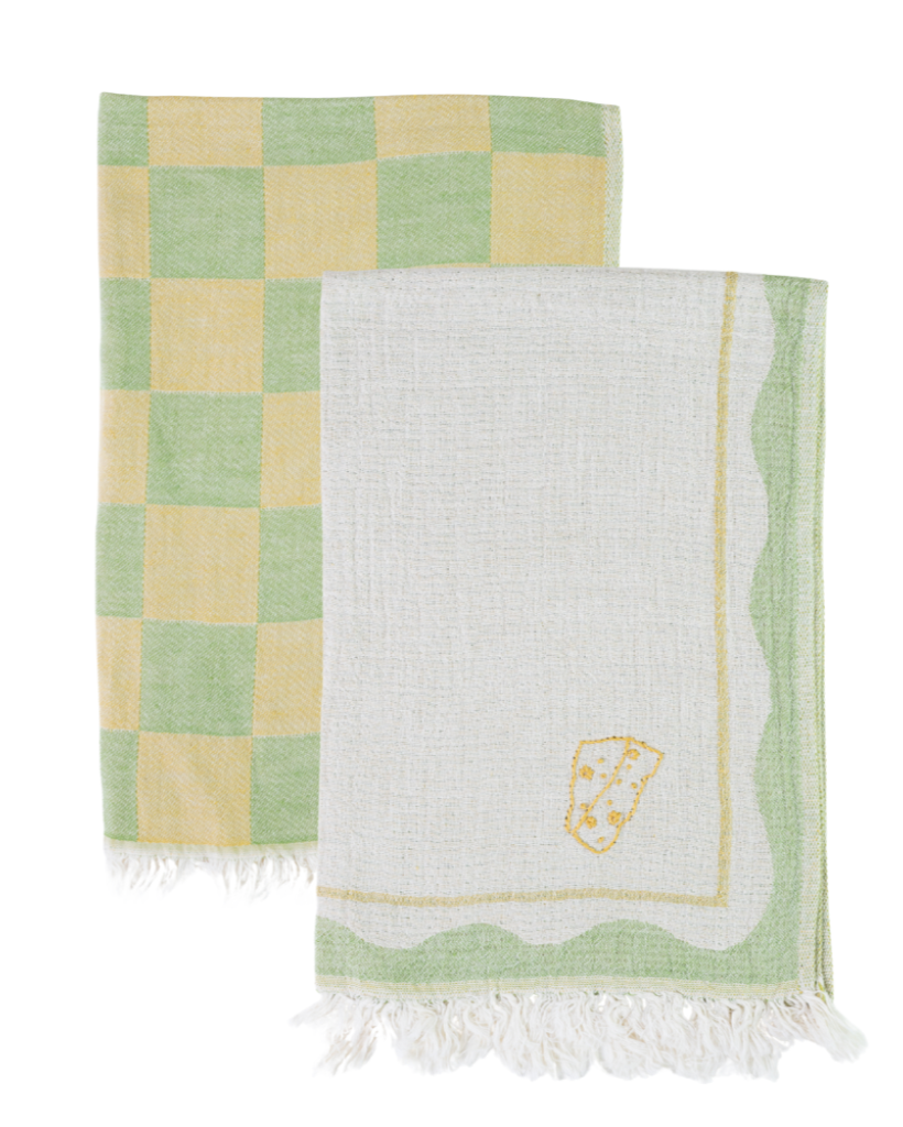 Two towels, one checkered green and yellow, the other white with a logo, on a white background.