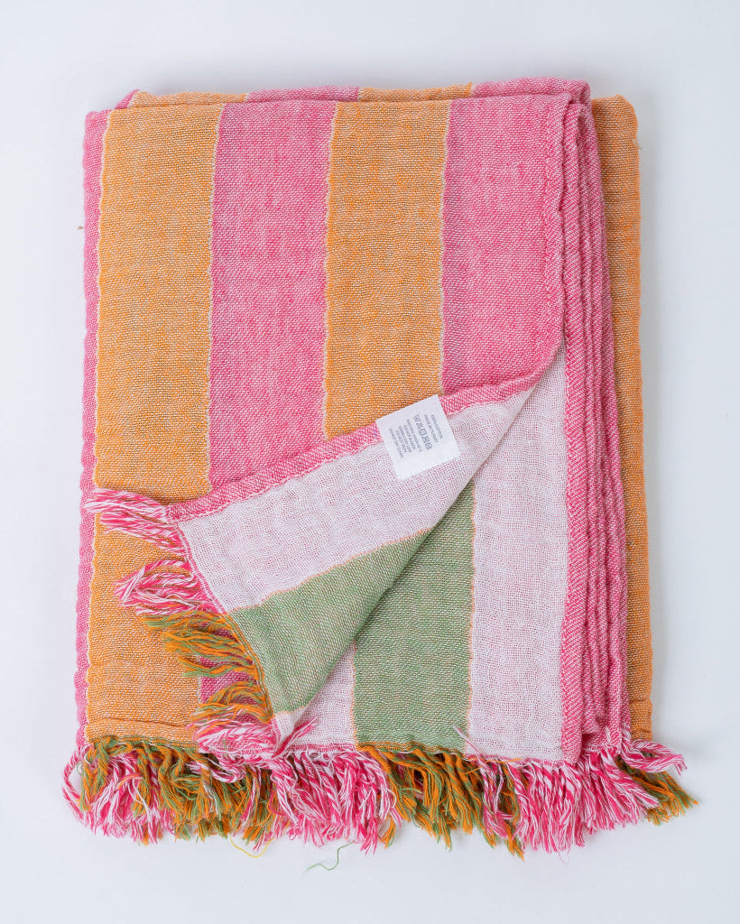 Colorful striped and folded body towel with frayed edges on a white background