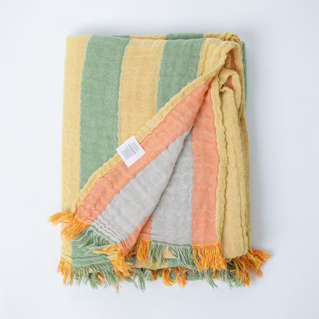 Colorful striped and folded body towel with frayed edges on a white background