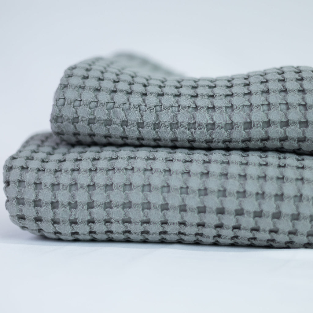 Two folded textured grey towels on a light grey background