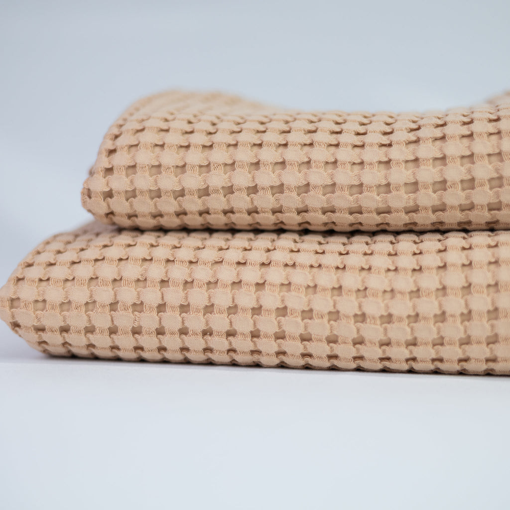 Two folded textured tea rose towels on a light grey background