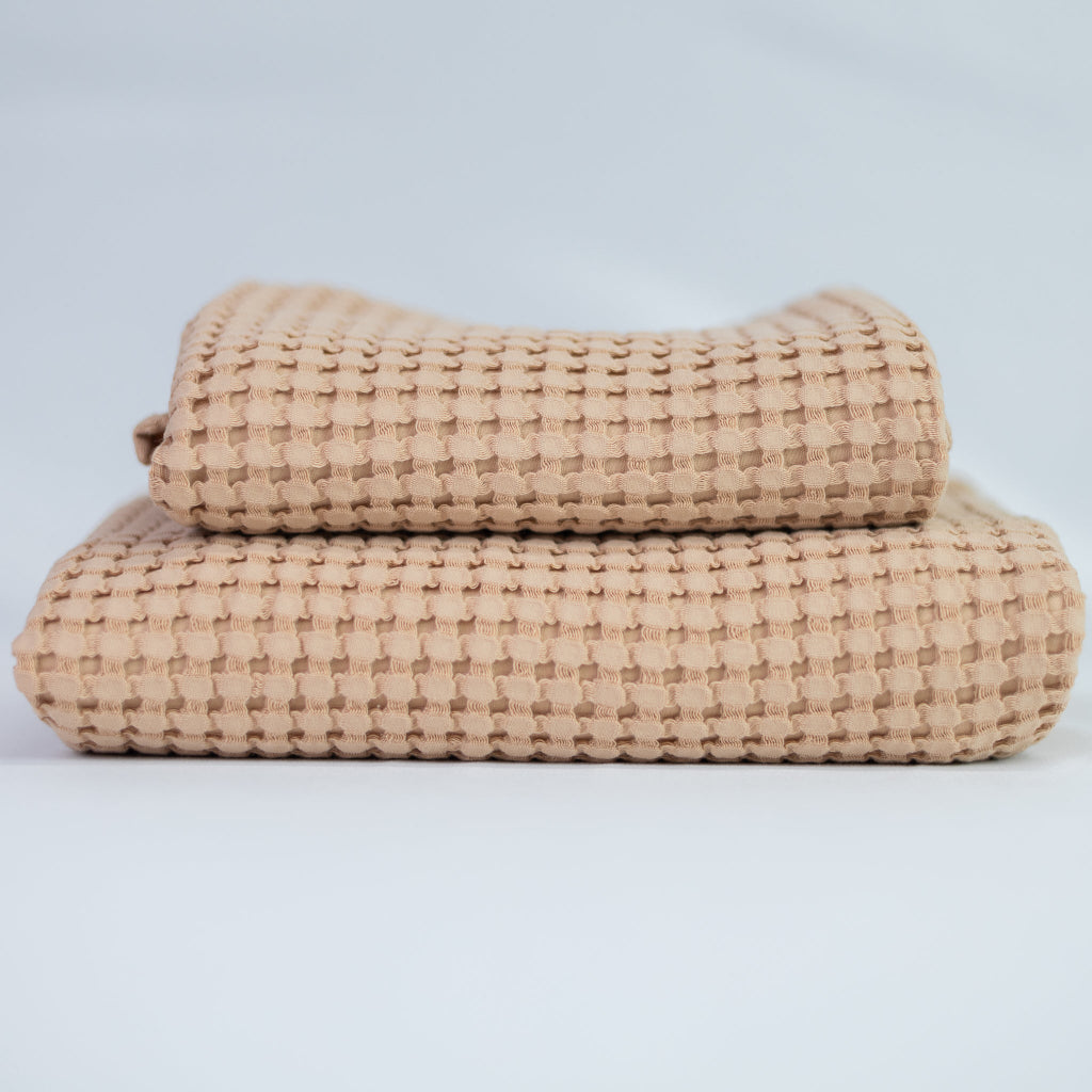 Two rose textured towels, one body and one hand, stacked against a white background