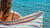 Closeup of a woman holding a multicolor Turkish towel in front of the sea