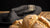 Loaf of bread on a wooden surface with a dark napkin in the background