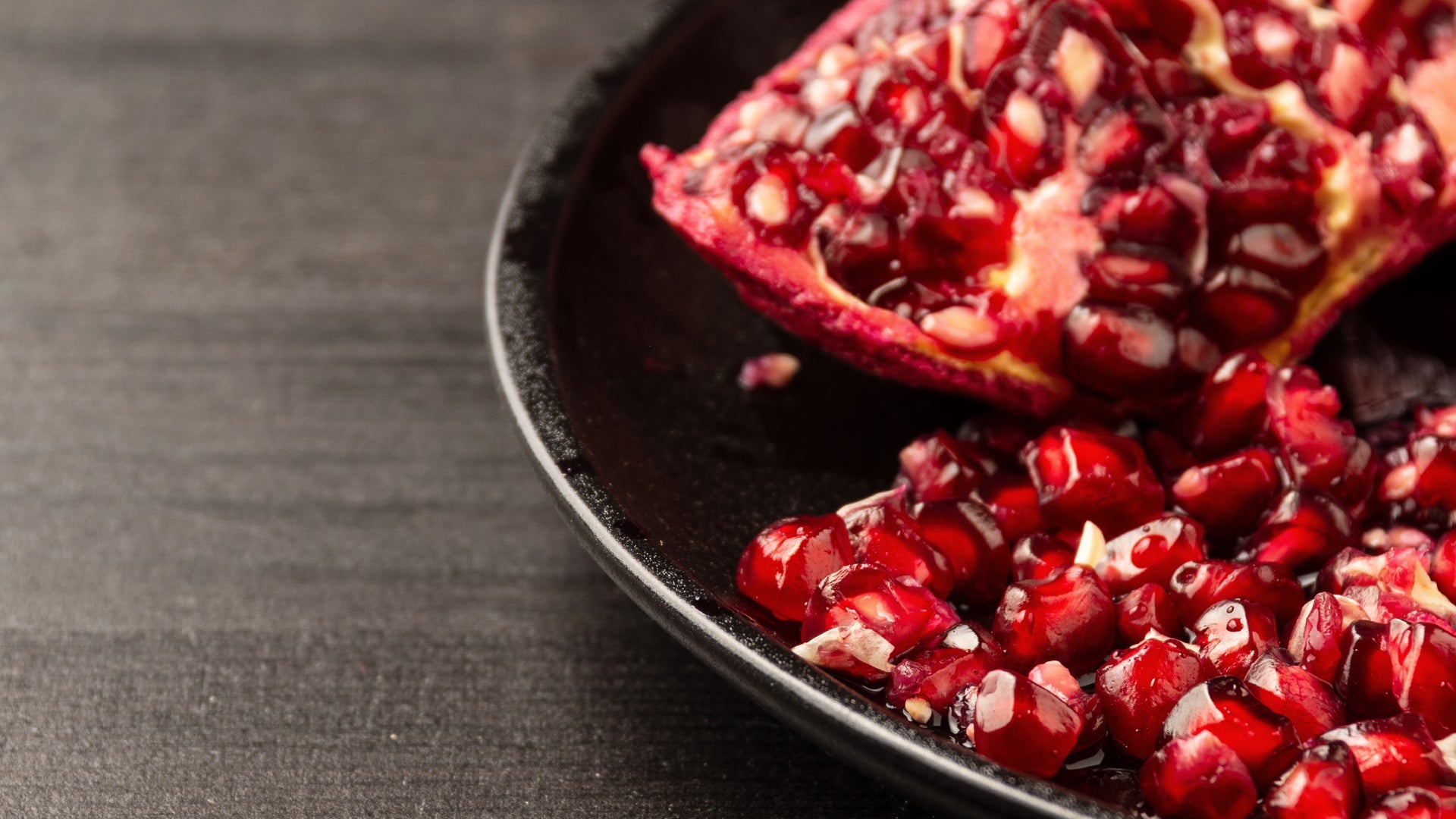 Pomegranate seeds on a dark surface