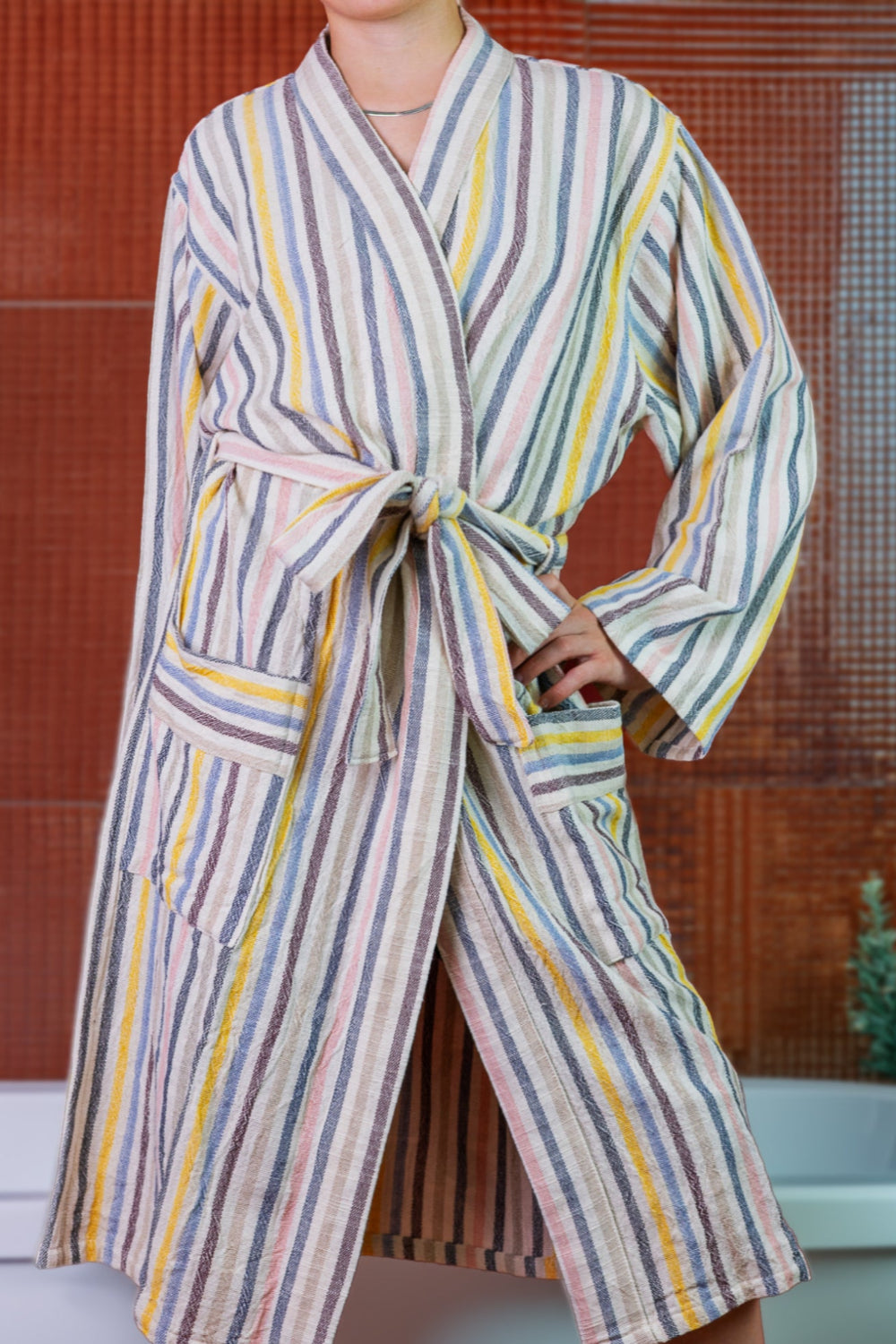 Woman in a striped bath robe in front of a bathtub and red tile