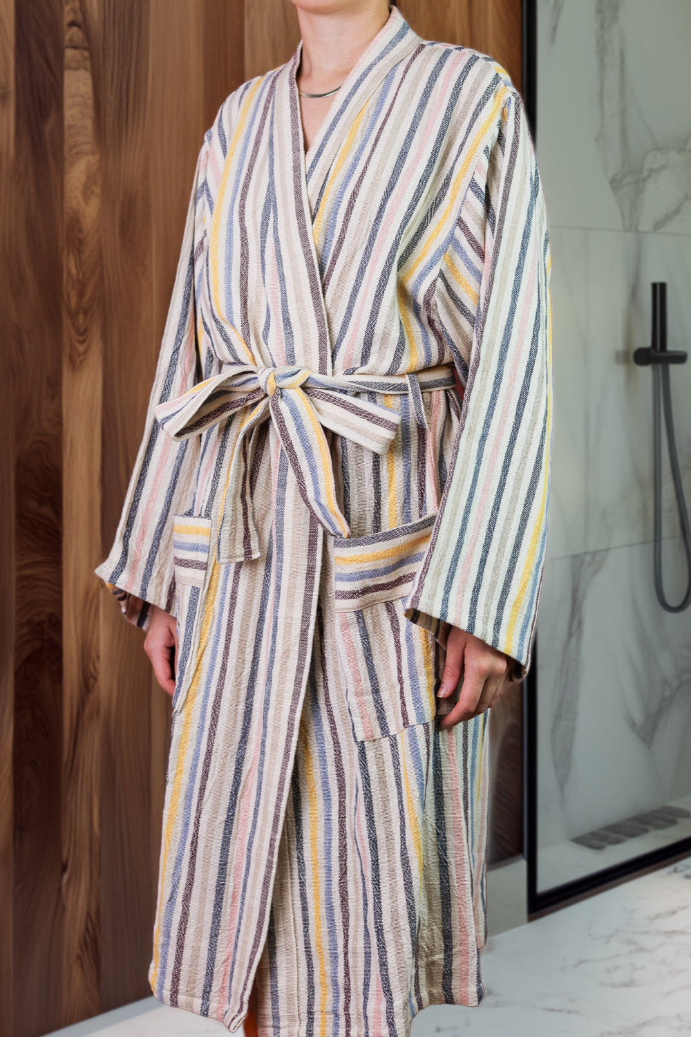 Woman in a striped bath robe in front of a shower and wood panel wall