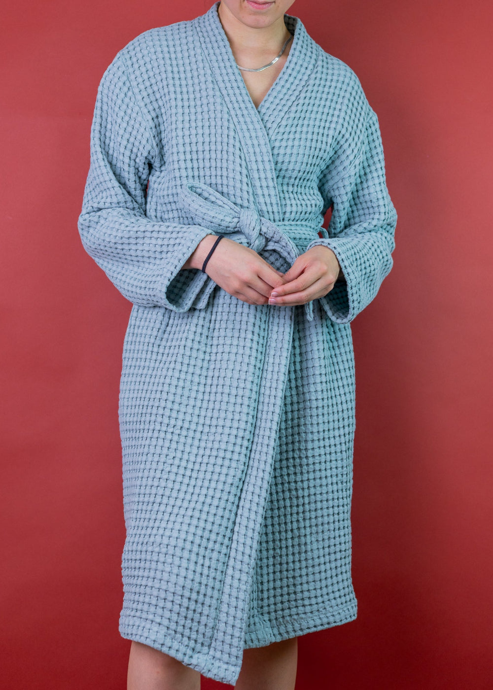 Woman wearing a blue waffle robe against a red background