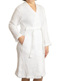 Woman wearing a white waffle bath robe standing against a white background