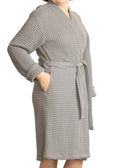 Woman wearing a grey waffle bathrobe standing against a white background