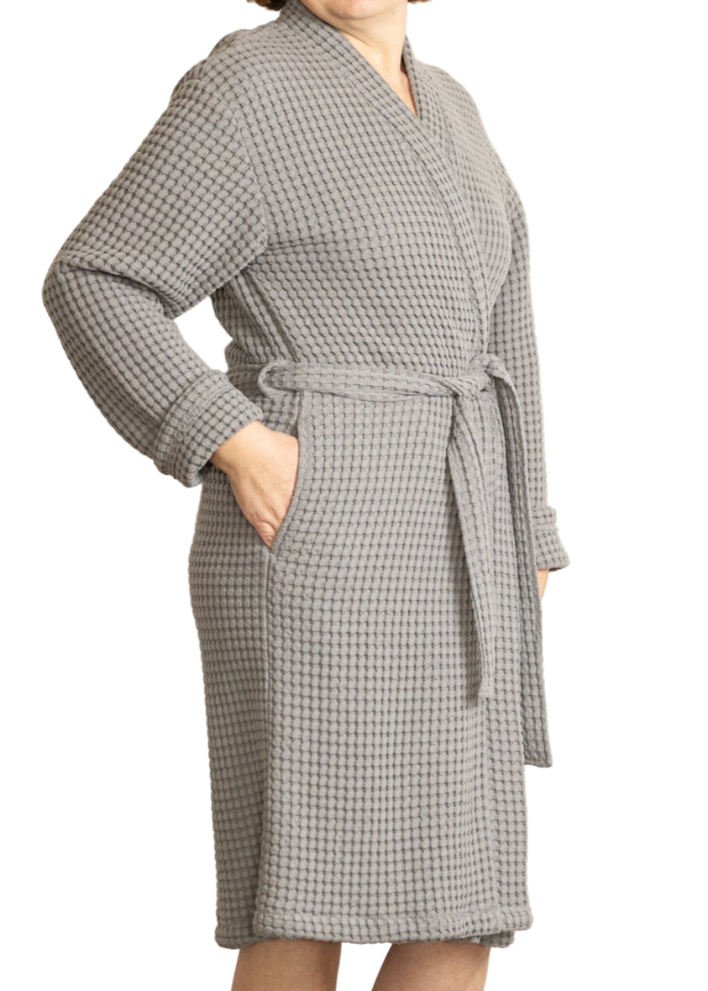 Woman wearing a grey waffle bathrobe standing against a white background
