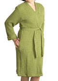 Woman wearing a sage green waffle bathrobe standing against a white background