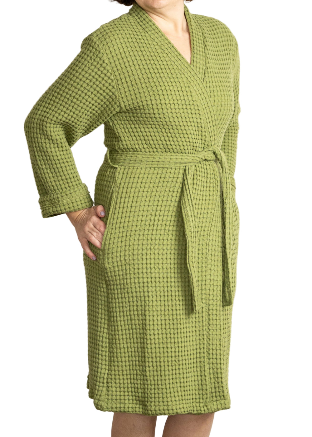 Woman wearing a sage green waffle bathrobe standing against a white background