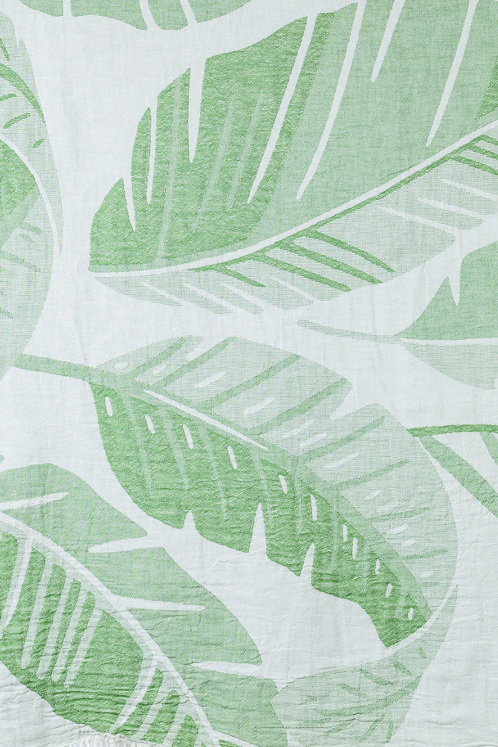 Close-up of beach towel with green leaf pattern on a white background