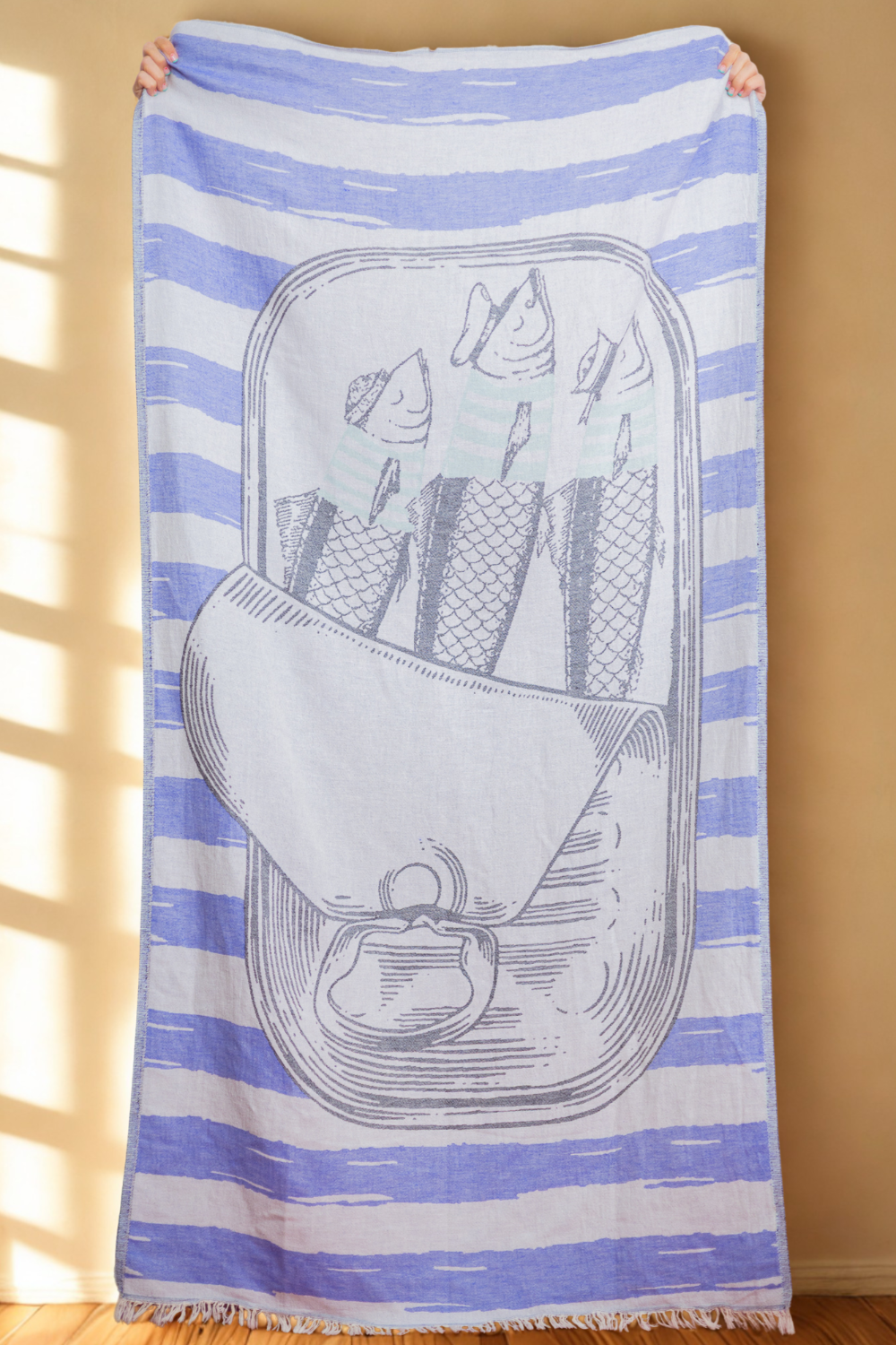 A blue and white striped Turkish beach towel with a jacquard design featuring a sardine tin.