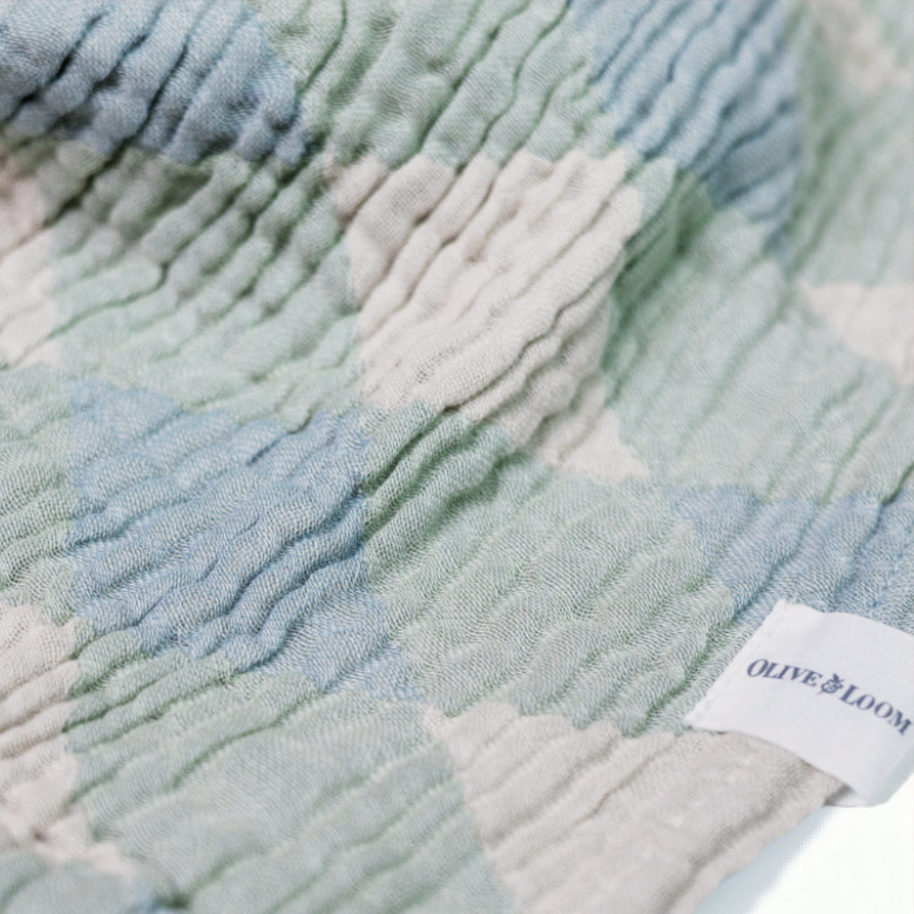 blanket with geometric pattern and &#39;Olive and Loom&#39; label on a white background