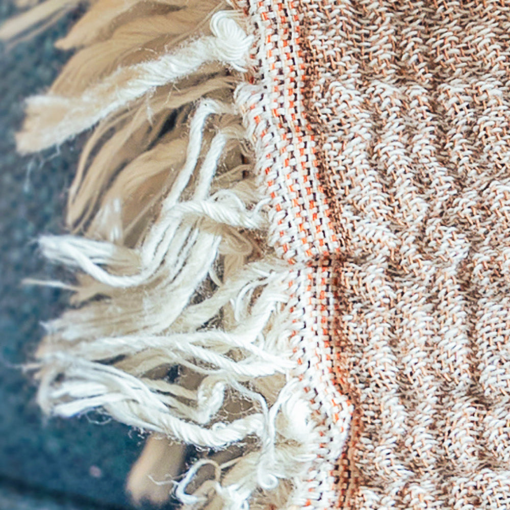 Close-up of a textured fabric with fringes and a ribbed pattern.