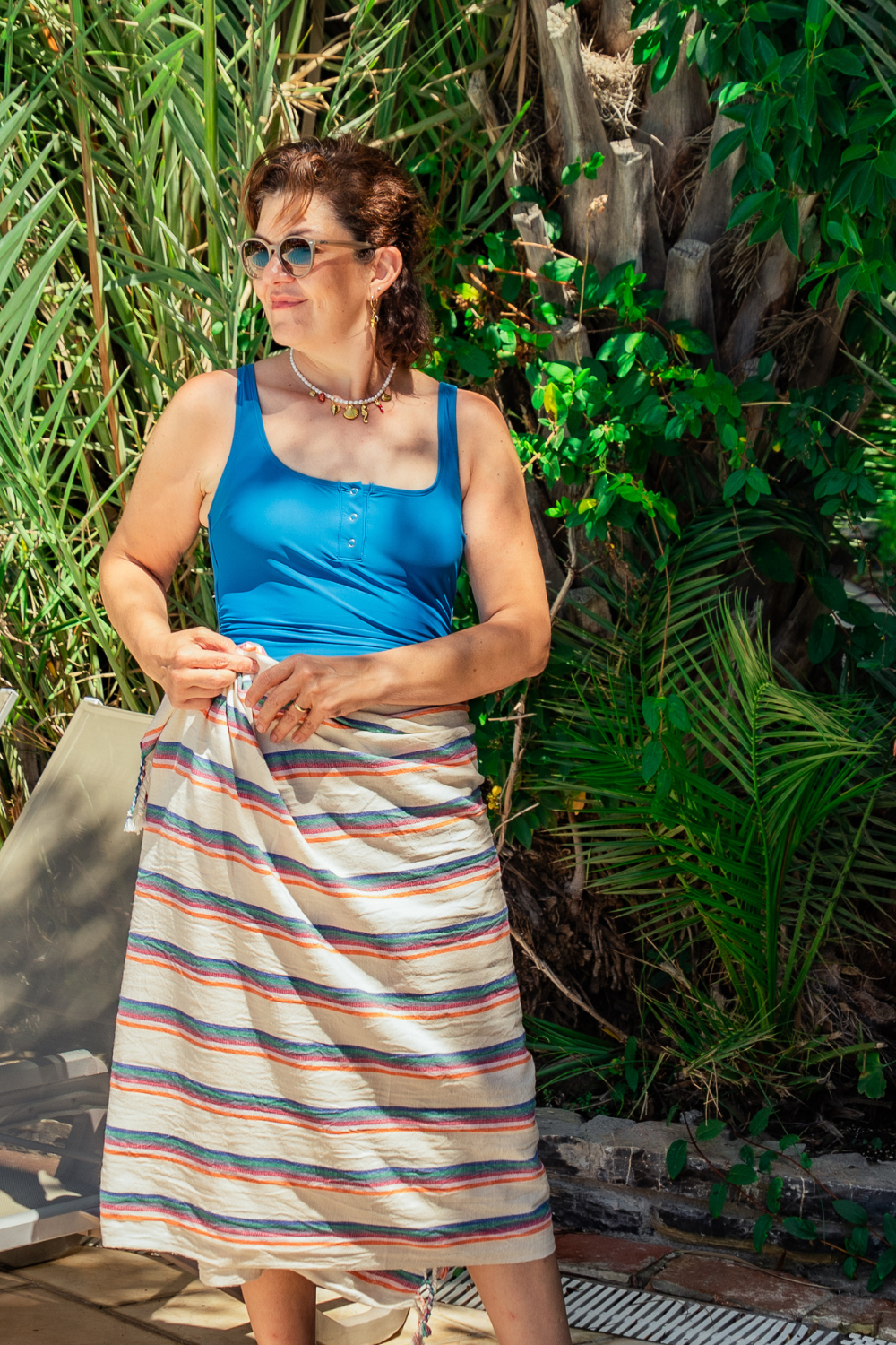 Woman wearing a blue top and striped skirt standing in a garden setting