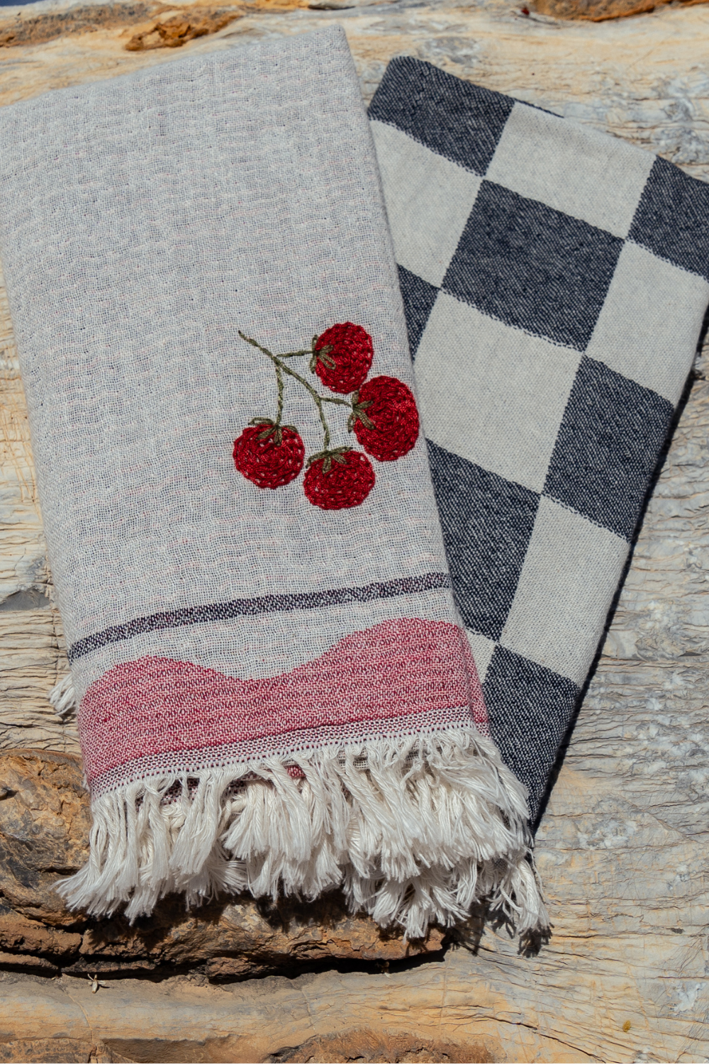 Two scarves on a wooden surface, one with cherry design and the other checkered.