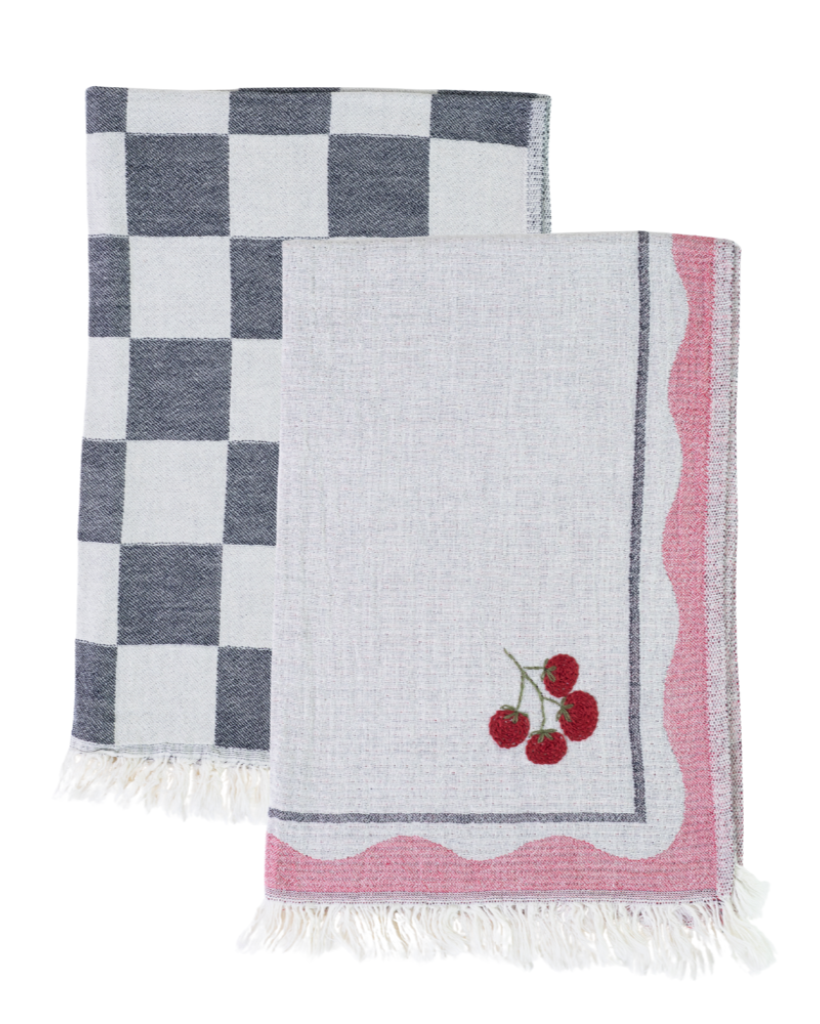 Two kitchen towels, one checkered and one with cherry design, on a white background