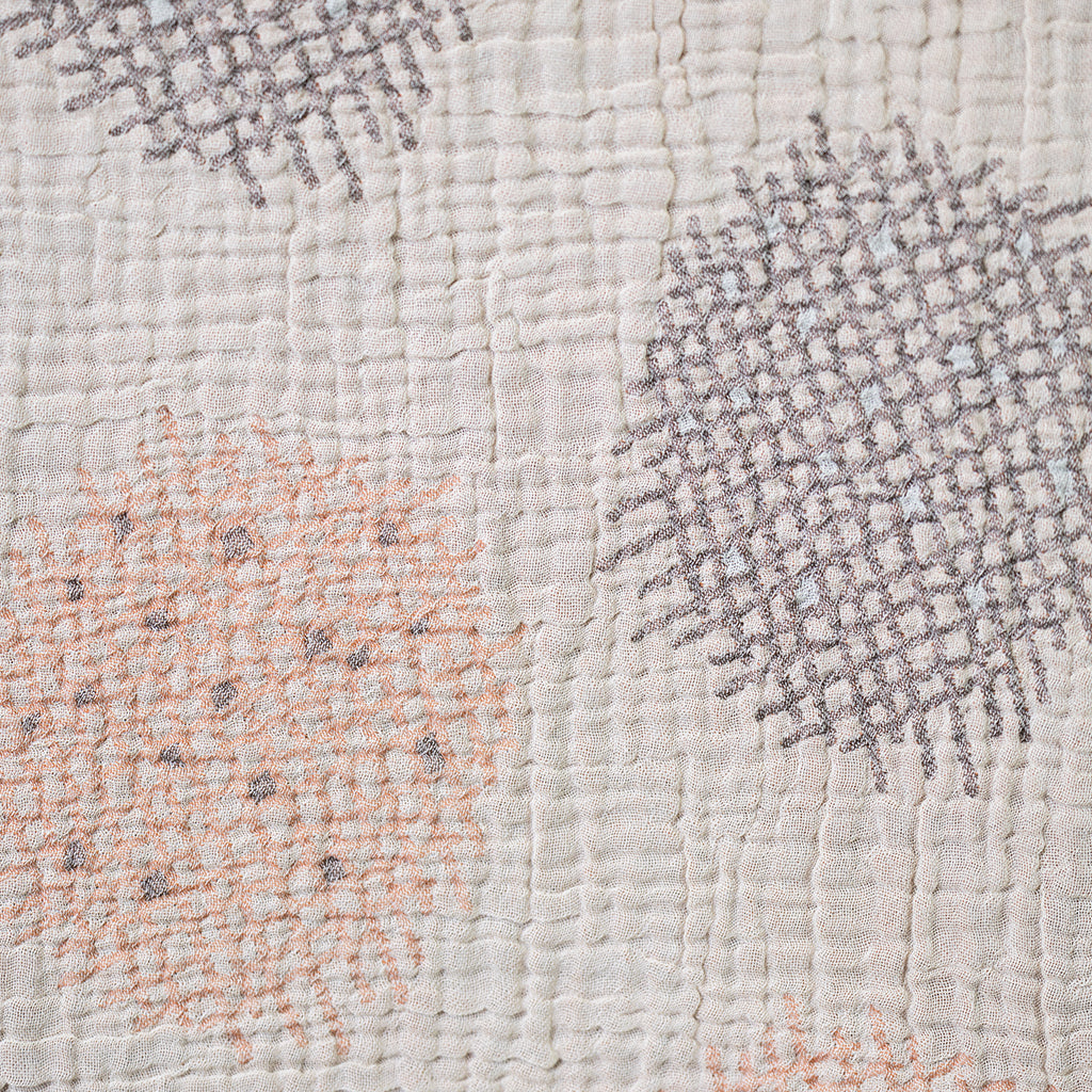 Close-up of textured fabric with geometric patterns in gray, pink, and white.