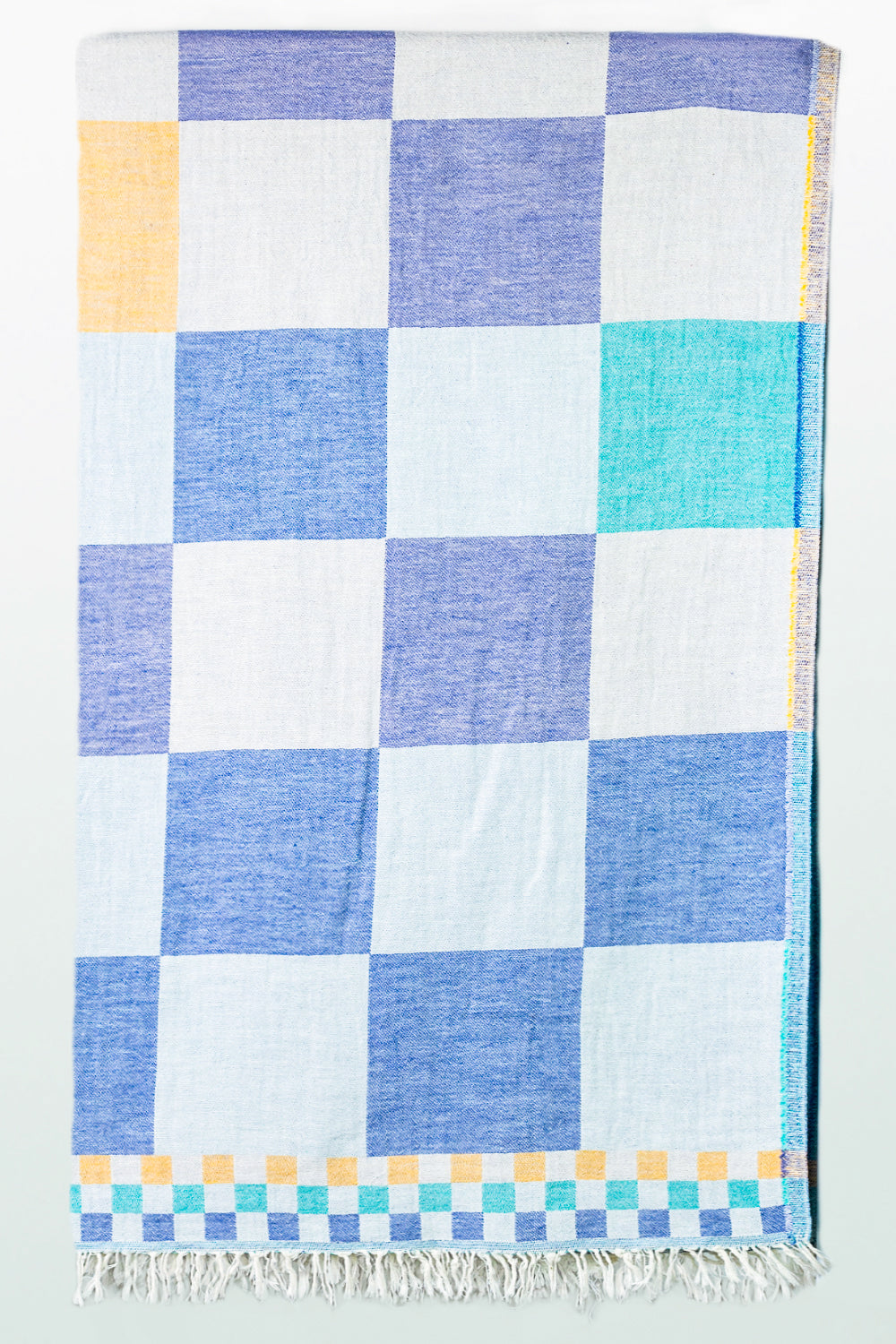 Checkered towel with blue, white, and yellow squares on a white background