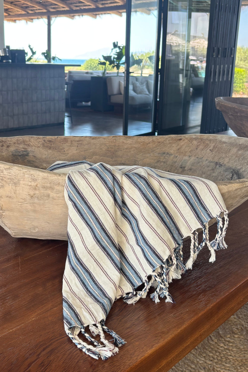 Striped towel draped over a wooden chair with a glass door in the background