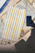 Striped Turkish peshtemal towel with yellow and gray stripes on a stone surface