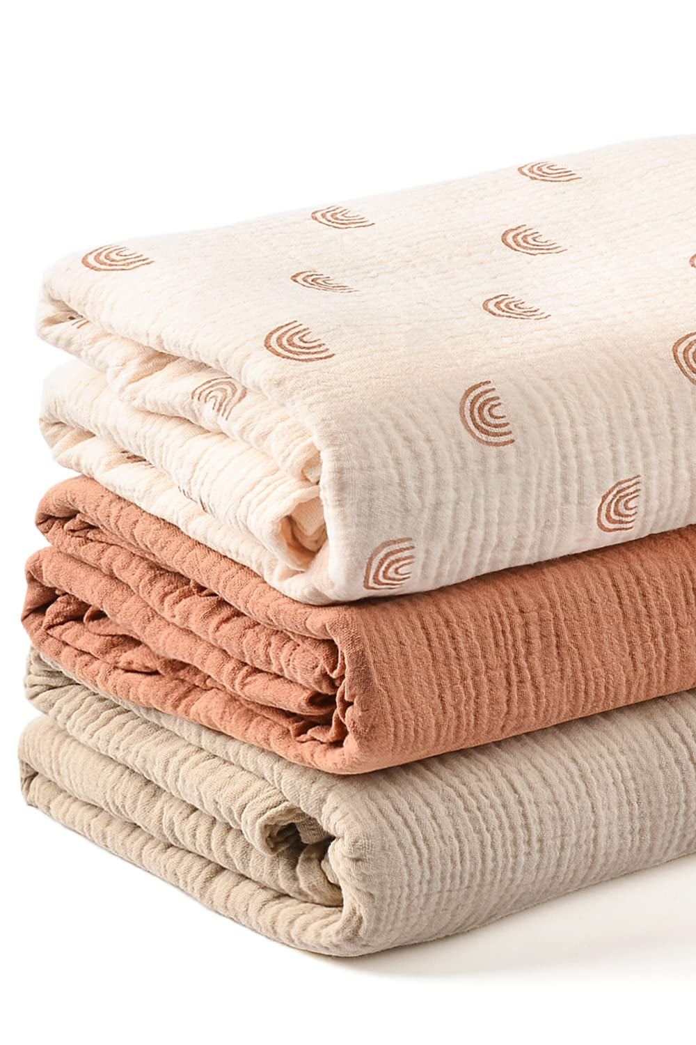 Stack of three folded fabric swaddles in beige, pink, and white with subtle patterns on a white background.