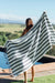 Person holding a striped towel by a pool with a scenic background