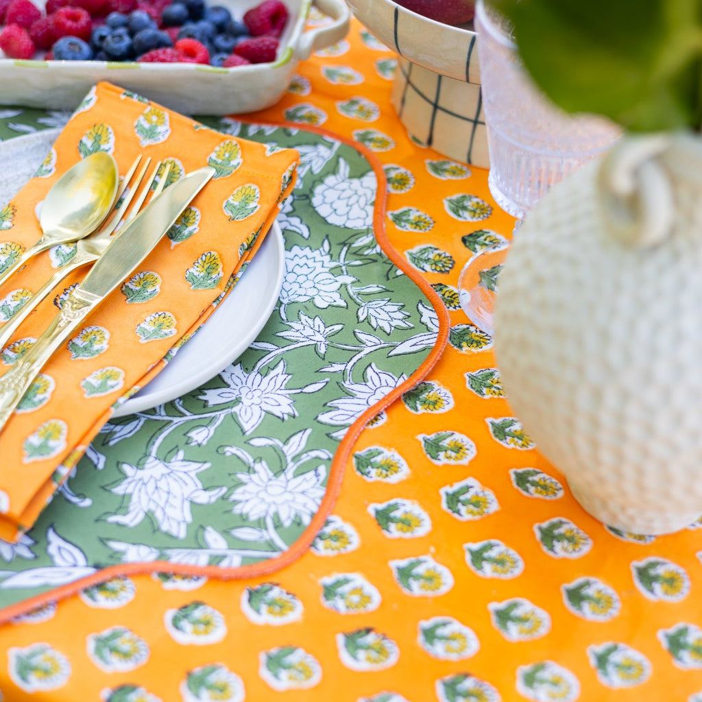 Colorful table setting with patterned placemats, cutlery, and fruit bowl.