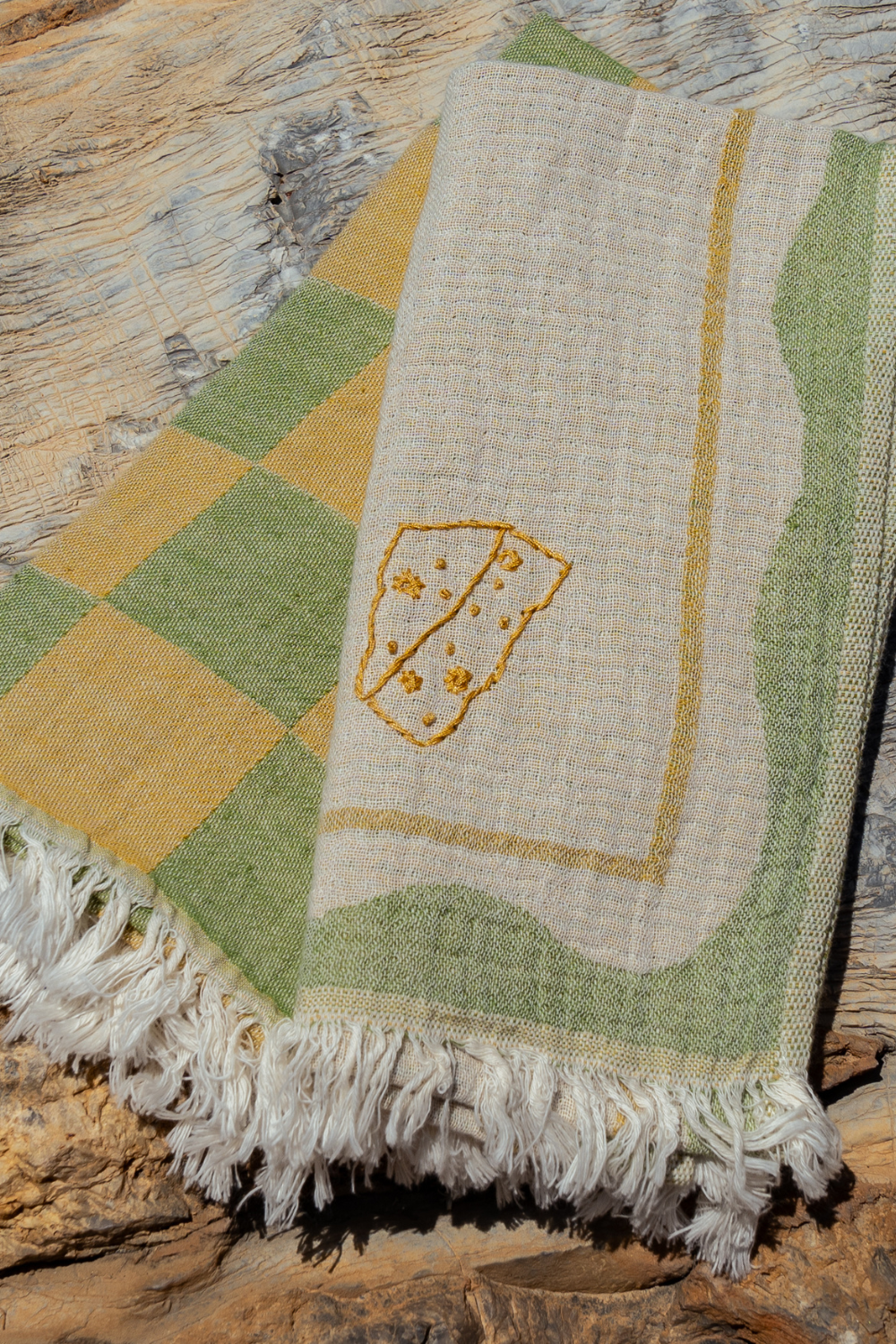 Textile with a geometric pattern and embroidered design on a wooden surface