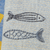 Two embroidered fish on a textured fabric background