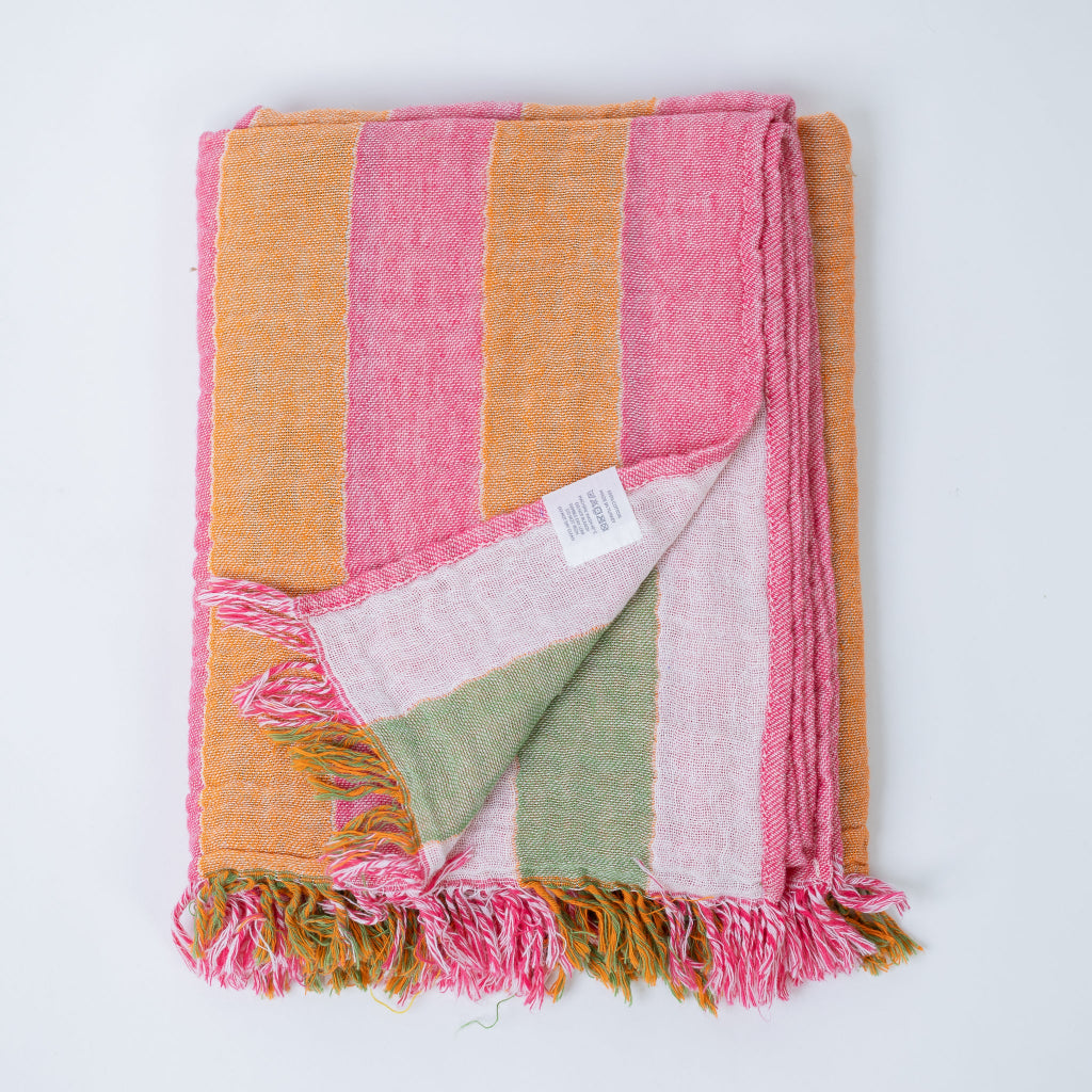 Colorful striped and folded body towel with frayed edges on a white background