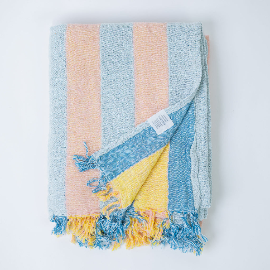 Colorful striped and folded body towel with frayed edges on a white background