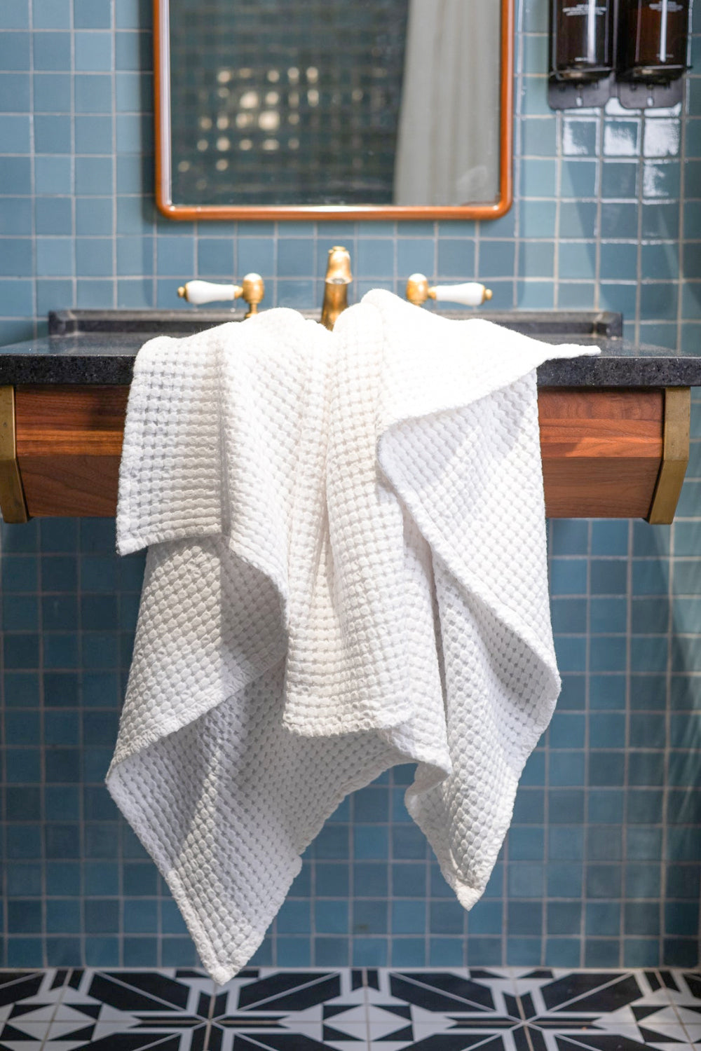 Bathroom with blue tiled walls, wooden vanity, and white towel.