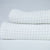 Two folded textured white towels on a light grey background