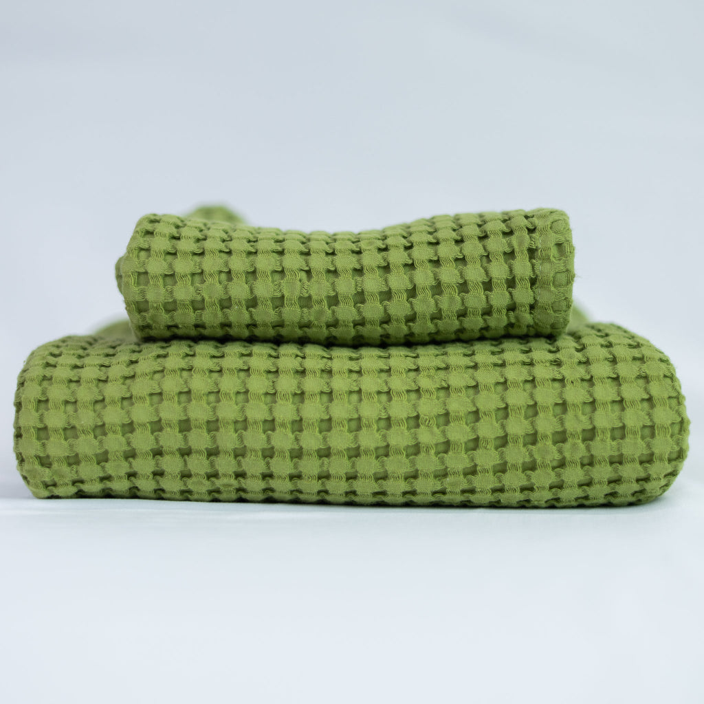 Two green textured towels, one body and one hand, stacked against a white background