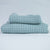 Two blue textured towels, one body and one hand, stacked against a white background